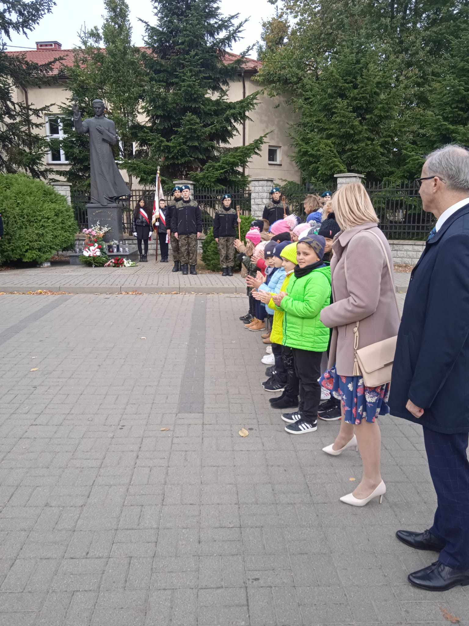 władze miasta Ząbki i dzieci. w tle pomnik ks. Jerzego Popiełuszki.