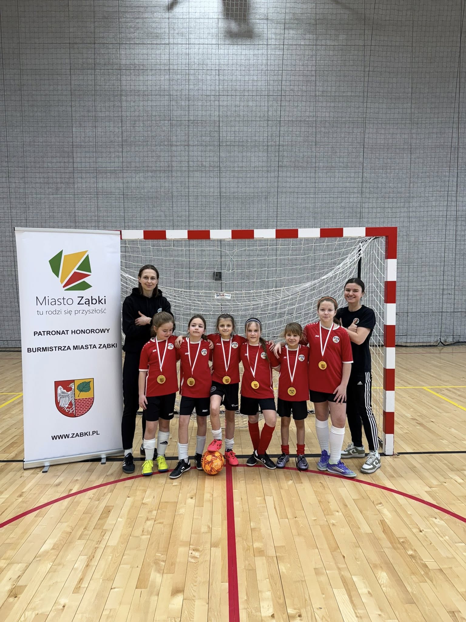 dziewczęta z trenerkami Ząbkovii na tle bramki piłkarskiej